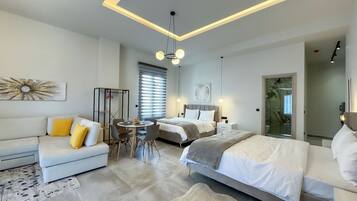 Una habitación de hotel moderna con sofá, una mesa de comedor, cama y zona de ducha.
