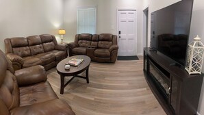 A living room with a brown leather sectional sofa, a small round coffee table, and a flat-screen TV. - Newly Remodeled 3-BR in heart of Marion (Marion)
