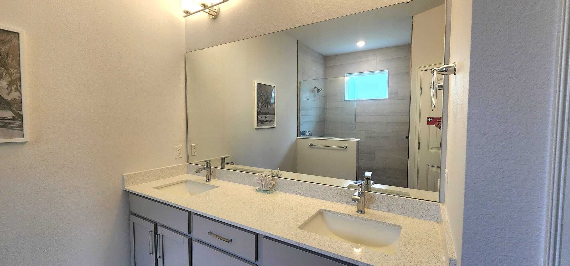 A bathroom with two sinks, a large mirror, and a glass shower enclosure.