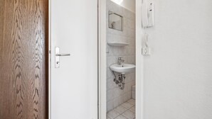 Een badkamer met een wit wastafelmeubel, spiegel en een telefoon bevestigd aan de muur.