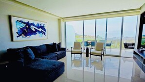 Un salon moderne avec une grande fenêtre, un canapé et deux fauteuils.