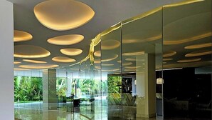 Un intérieur moderne avec des cloisons en verre, un plafond incurvé agrémenté de luminaires circulaires et un sol réfléchissant.
