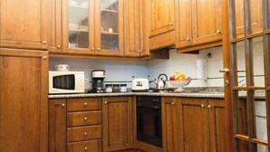 Una cocina con armarios de madera, microondas, cafetera y tostadora.
