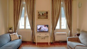 Una sala de estar con televisor, dos sofás, una mesita y un radiador.