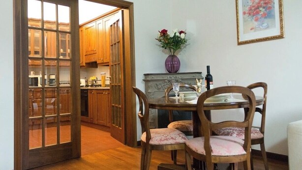 Un comedor con una mesa y sillas, un florero con flores y un cuadro en la pared.