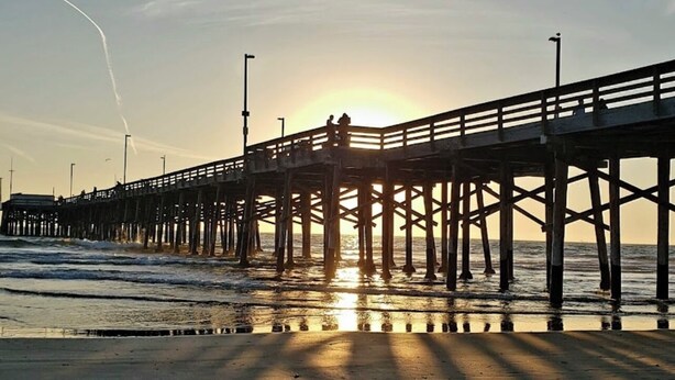 A pier extending into the water with a sunset in the background. -  Luxury home in Newport Beach city Near UCI (Newport Beach)