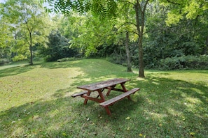 A picnic table in a grassy area surrounded by trees. - Butterfly Crossing | Private Lake, Hot Tub (Logan)