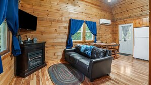 Un intérieur de chalet chaleureux avec une cheminée, un canapé en cuir et un coin repas.