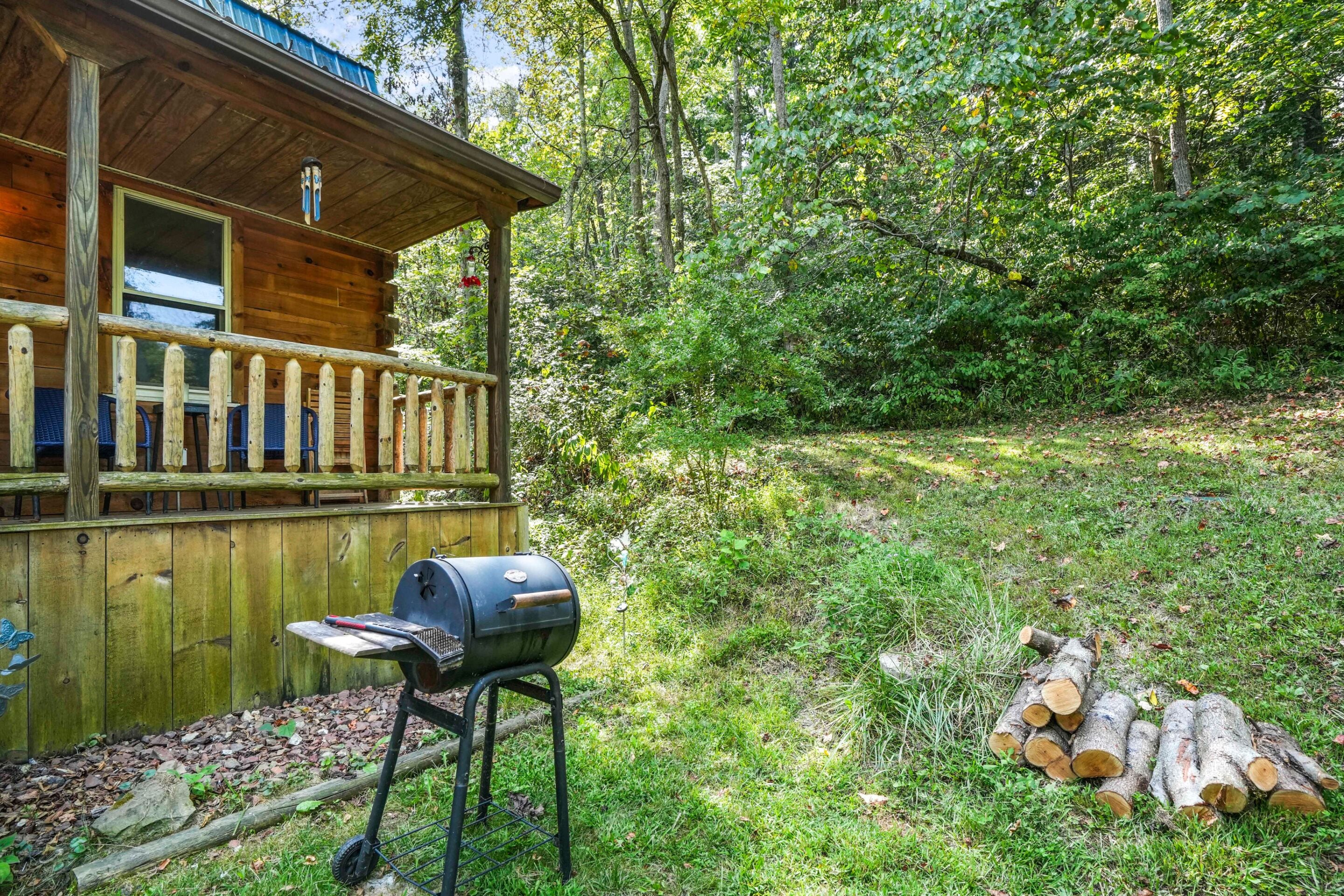 Eine Holzhütte mit Veranda, Grill und Holzstoß.