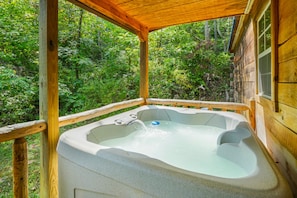 Un jacuzzi en una cabaña de madera rodeada de vegetación exuberante.