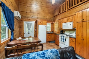 A wooden cabin interior with a dining table, kitchen area, and a cozy seating area. - Butterfly Crossing | Private Lake, Hot Tub (Logan)