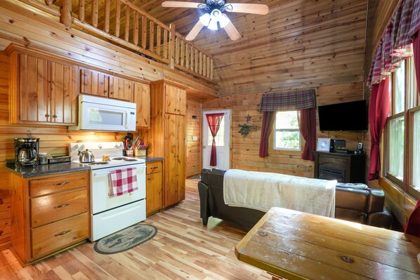 A cabin interior with wooden walls, a kitchenette, a sofa, and a television.