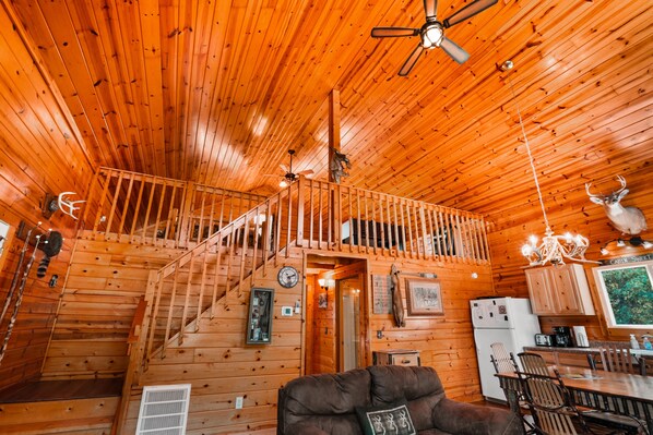A wooden cabin interior with a staircase, a dining area, and a kitchen.