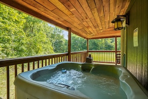 A hot tub on a wooden deck with a view of a green landscape.