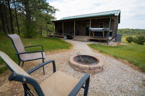 A rustic cabin with a fire pit, outdoor seating, and a porch.