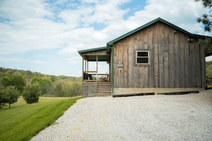 A wooden barn with a covered porch and a gravel driveway.