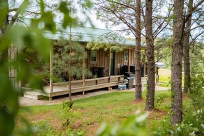 A wooden cabin with a covered porch, a grill, and a small deck.