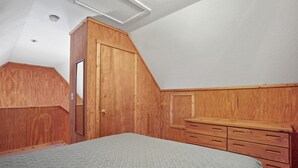Ein Schlafzimmer mit einem Holfischschrank, einem Bett mit gemustertem Überwurf und einer Holzkommode.