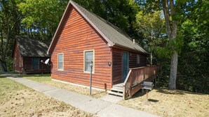 A wooden cabin with a porch, a small window, and a door. - Retreat Cabin #2 | Hocking Hills,  Pet Friendly (Logan)