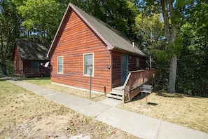 A wooden cabin with a porch, a small window, and a door.