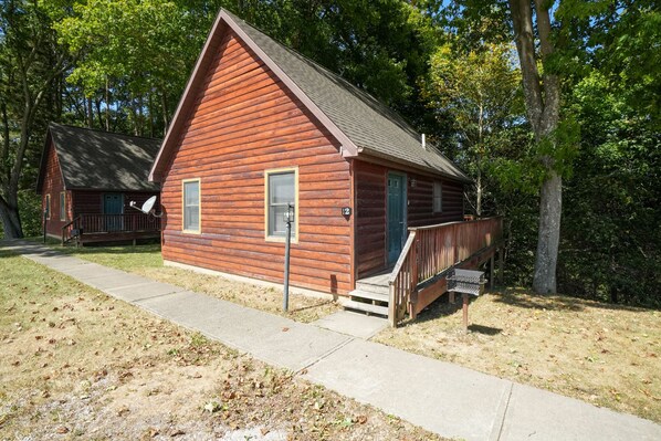 A wooden cabin with a porch, a small window, and a door.