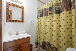 A bathroom with a white sink, wooden cabinet, mirror, and a shower curtain with a star pattern.