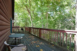 A wooden deck with a red railing, surrounded by trees.
