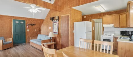 Un intérieur de chalet chaleureux comprenant un coin repas, une cuisine et deux canapés en bois.