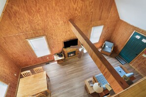 Una habitación compacta con piso de madera, chimenea, televisor, mesa de comedor y dos zonas de estar.