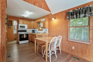 A wooden interior with a kitchen, dining table, and chairs.