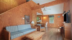 Una sala de estar con muebles de madera, un sofá, una mesa de centro y un comedor.