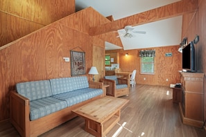 A wooden-furnished living room with a sofa, coffee table, and a dining area.