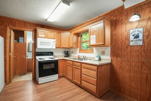 A kitchen with wooden cabinets, a white countertop, a stove, and a microwave.