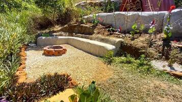 Un jardín con una jardinera de hormigón curva, un camino de grava y diversas plantas.