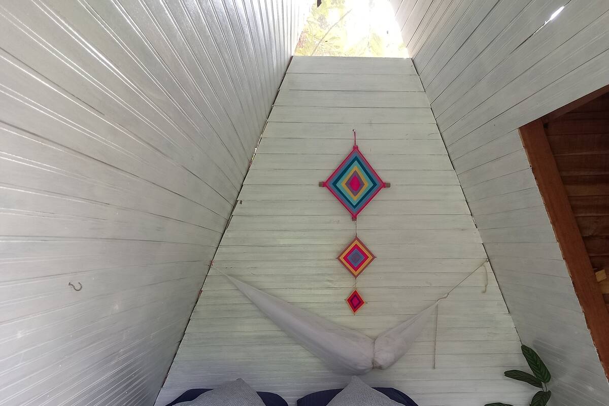 Una habitación triangular con una cama, almohadas y un adorno colgante.