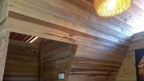 Un interior de madera con techo inclinado, una lámpara colgante y una planta en maceta.