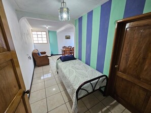 A bedroom with a bed, a chair, a window, and a door. - Casa Santander Panajachel (Panajachel)