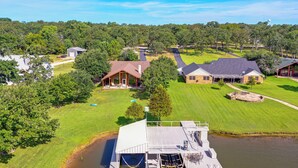 A lakeside property with a dock, a large house, and a well-maintained lawn. - ‘Rhodes Retreat’ w/ Dock on Cedar Creek Lake! (Log Cabin)