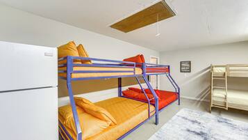 A bunk bed room with a wooden ladder, a white wall, and a framed picture on the wall.