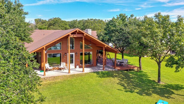 A two-story wooden house with a covered patio and a lawn. - ‘Rhodes Retreat’ w/ Dock on Cedar Creek Lake! (Log Cabin)