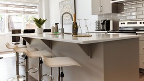 Una cocina moderna con una isla grande, taburetes de bar, electrodomésticos de acero inoxidable y una planta decorativa.