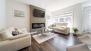 Una sala de estar moderna con un sofá, una mesa de centro y un televisor montado en la pared.