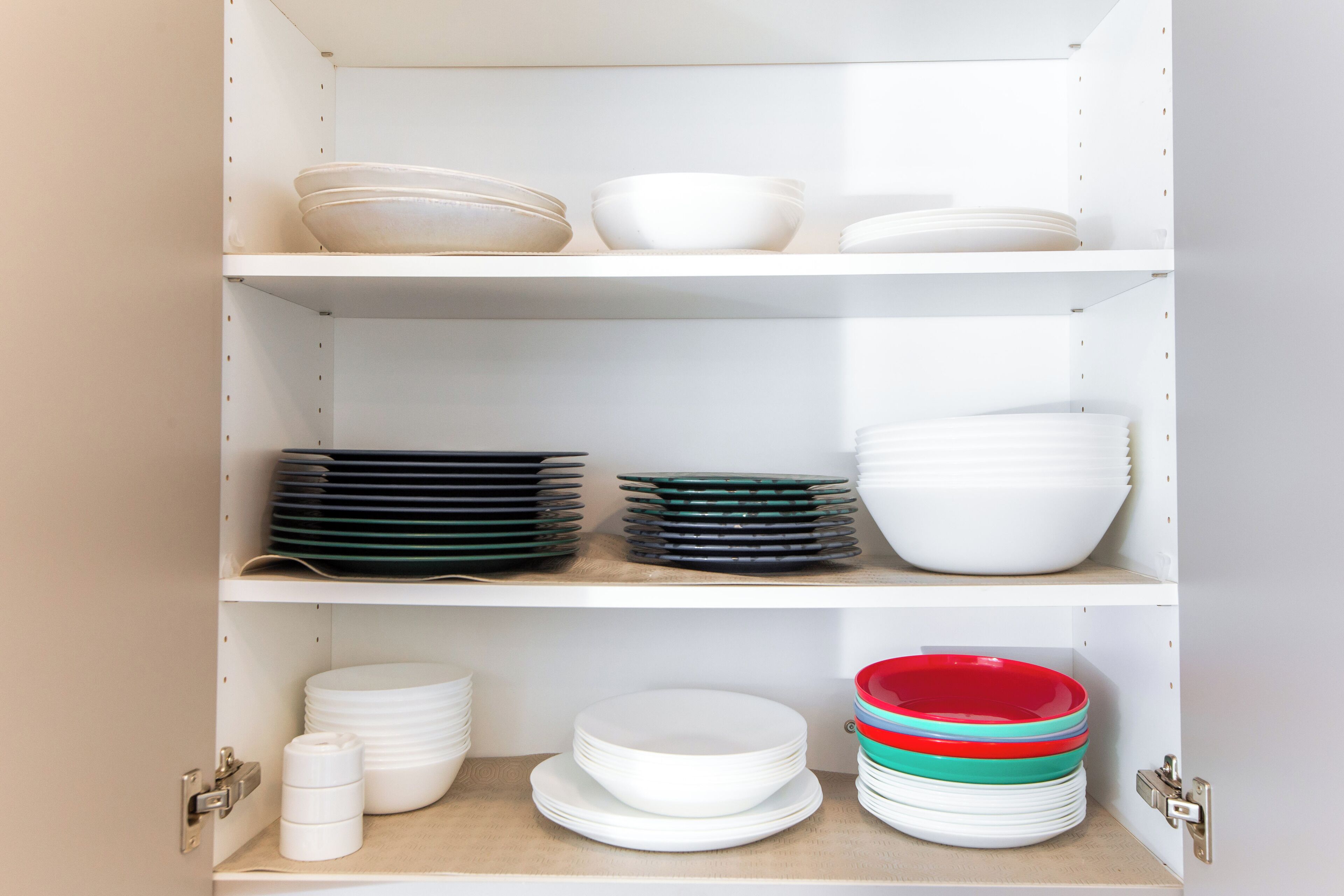 A white shelving unit with various plates and bowls organized on different shelves.