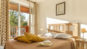 Un dormitorio con una cama grande, dos mesitas de noche, una ventana con cortinas y un balcón.