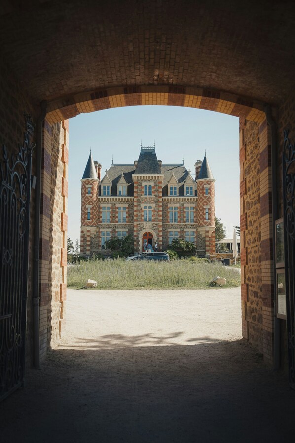 A large brick building with a central tower, through an archway.