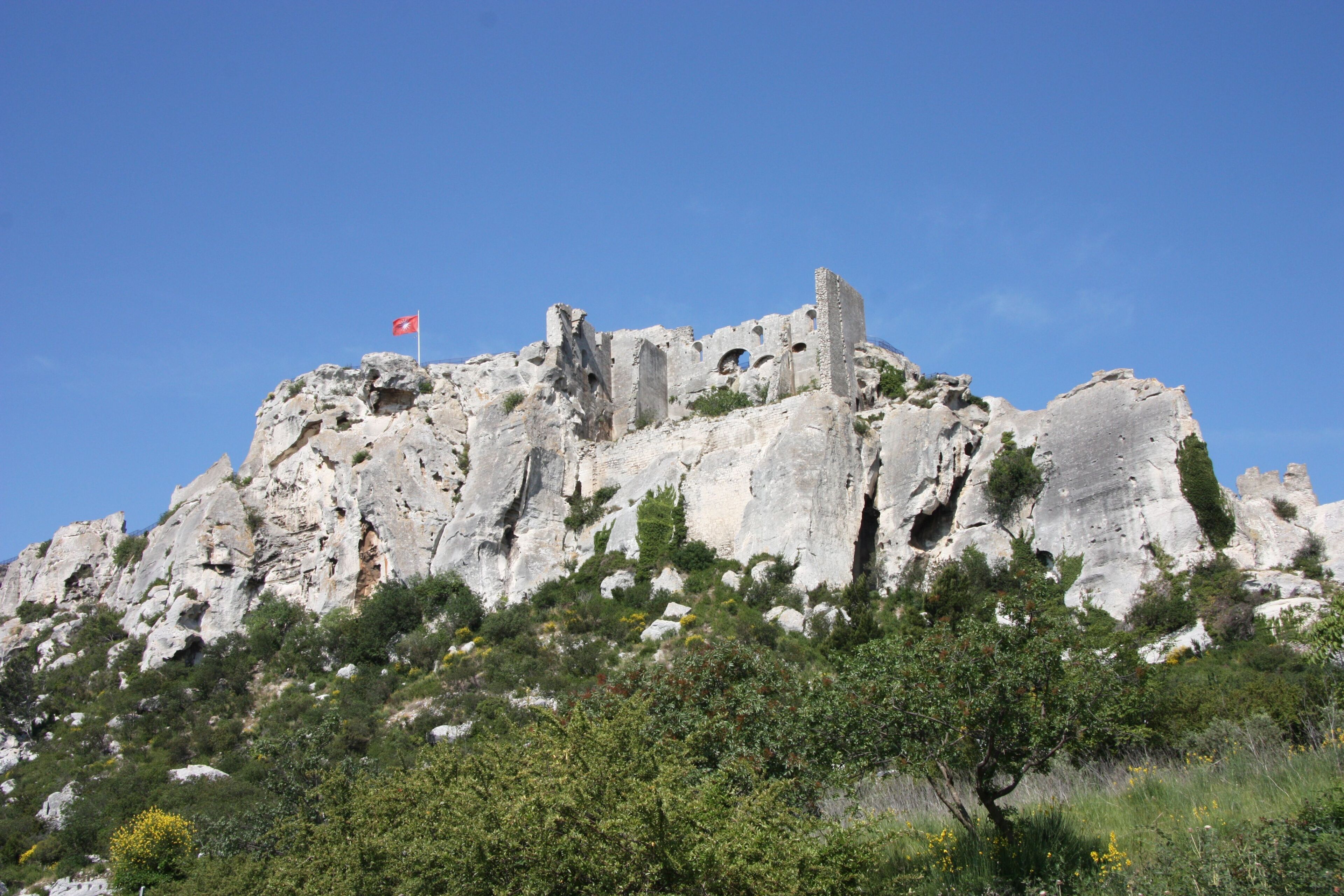 A rocky cliff with ruins and a flag.