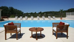 Un espace piscine avec des chaises longues et une table en bois.
