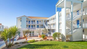 Un hotel con varios balcones, una recepción y un jardín bien cuidado.