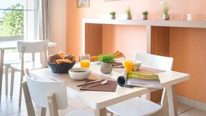 Una mesa de desayuno con pan, jugo y una planta.