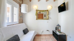 A room with a white sofa, a mirror with a decorative frame, a television, and a small table with a lantern. - Apartment 'La Torre' with Wi-Fi and Air Conditioning (Alicante (Alacant))